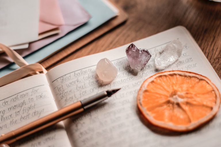 journal and pen with crystals and dried orange slice