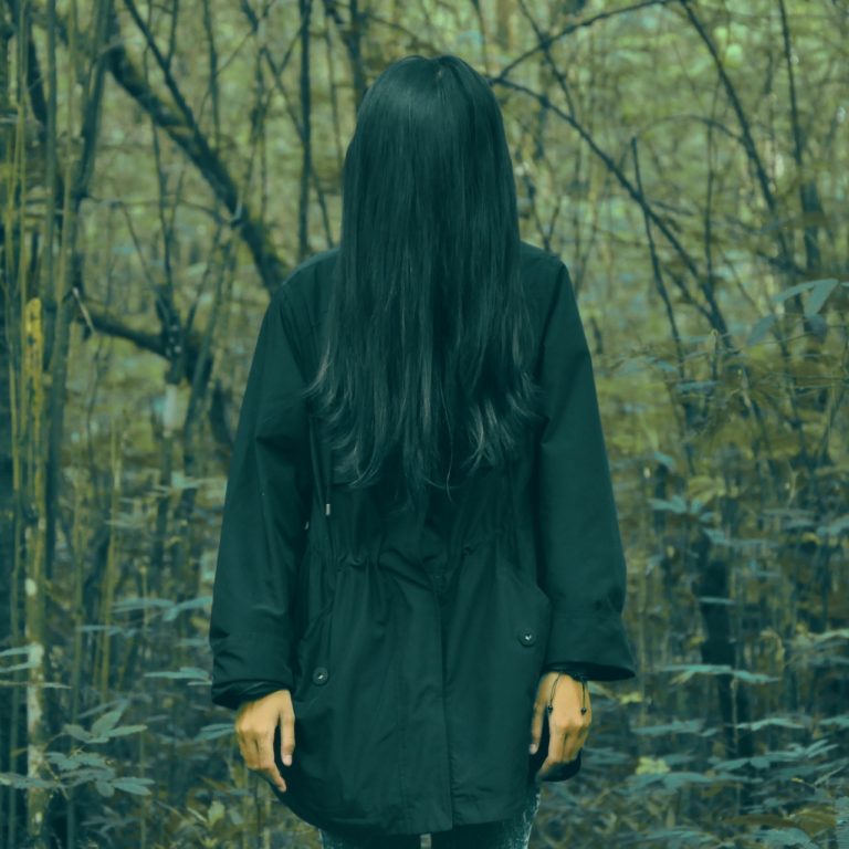 mourning girl in forest with face covered