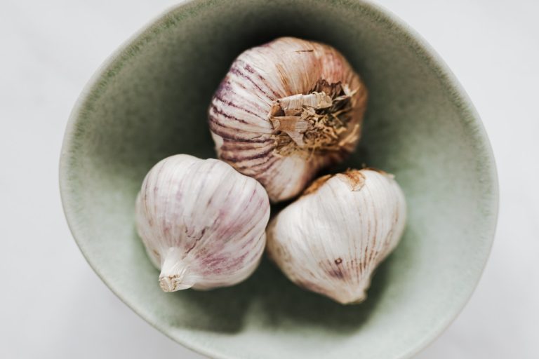 3 garlic bulbs in a grey bowl