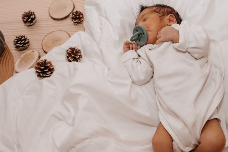 baby with pinecones and wood slices