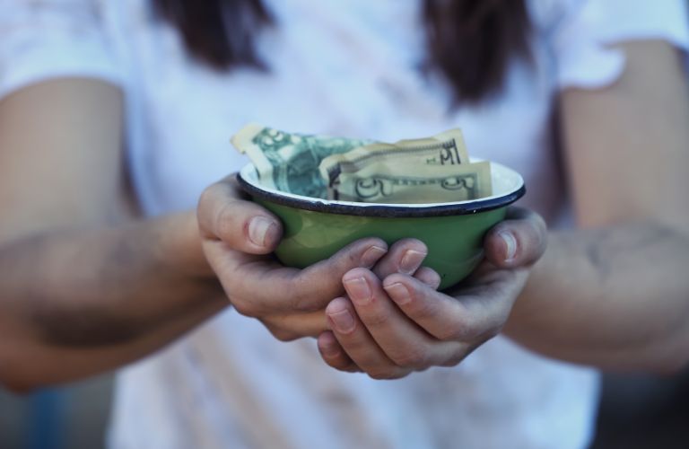 two hands holding a green money bowl filled with paper money