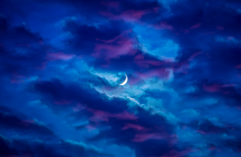 blue and purple cloudy night sky with a small, glowing crescent moon