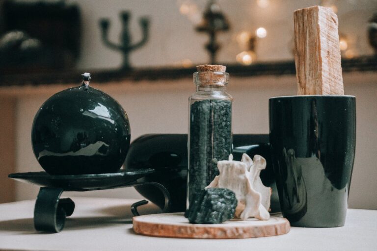 black witchcraft ritual supplies such as a crystal ball, black salt, and palo santo stick